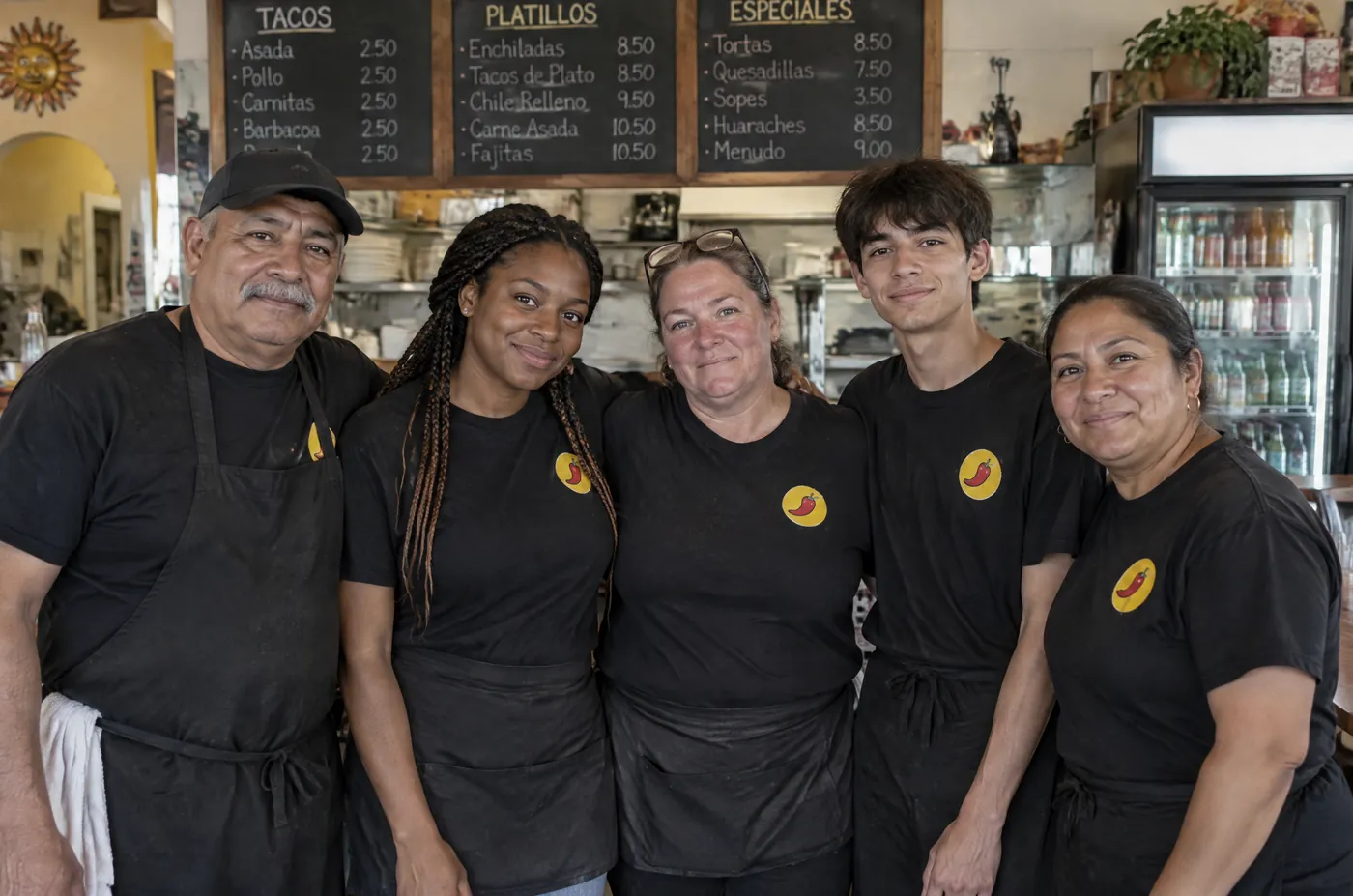 Restaurant staff in matching black shirts with a chili pepper logo